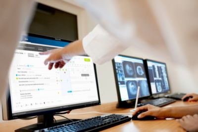 Healthcare professional interacting with Philips Tasy clinical informatics system on computer