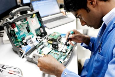 Technician repairing medical equipment in healthcare setting