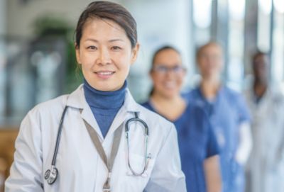 一名佩戴听诊器的临床医生与医疗团队一起站在医院里
