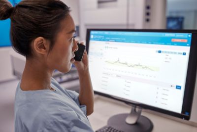 Un clínico revisando análisis de monitorización de pacientes en un panel de control de Philips en una estación de trabajo de un hospital