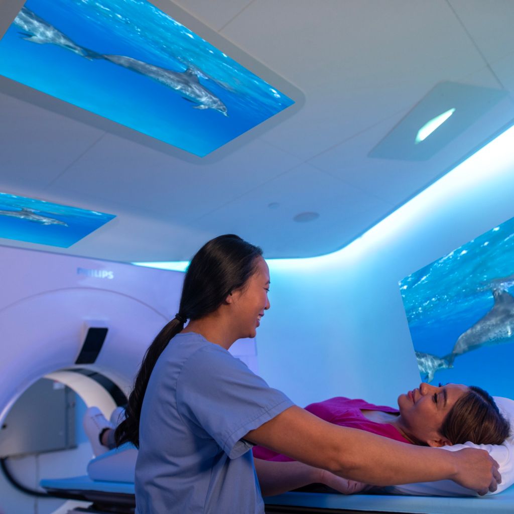 Spectral CT 7500, technician comforting patient prior to CT exam in exam room with Philips Ambient Experience.