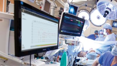 Surgical team performing operation with patient monitoring systems and medical displays in operating room