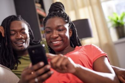 Two people sitting on a couch and relaxing with a smartphone