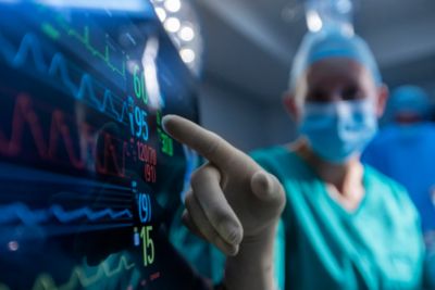 Profesional de la salud en un quirófano interactuando con la pantalla táctil del monitor de pacientes de Philips, que muestra signos vitales en tiempo real