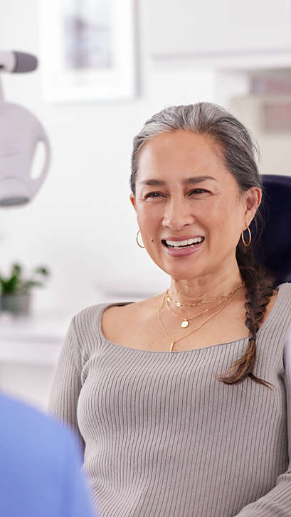 Smiling patient holding a shade guide close to her smile