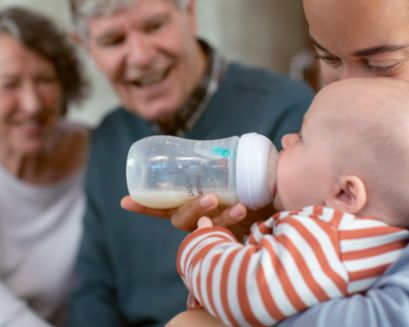 Grand-père donnant le biberon à son petit-fils/sa petite-fille