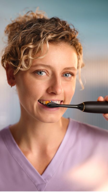En kvinna som borstar med en elektrisk Philips Sonicare-tandborste.