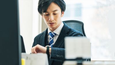 デスクで時間を確認する会社員