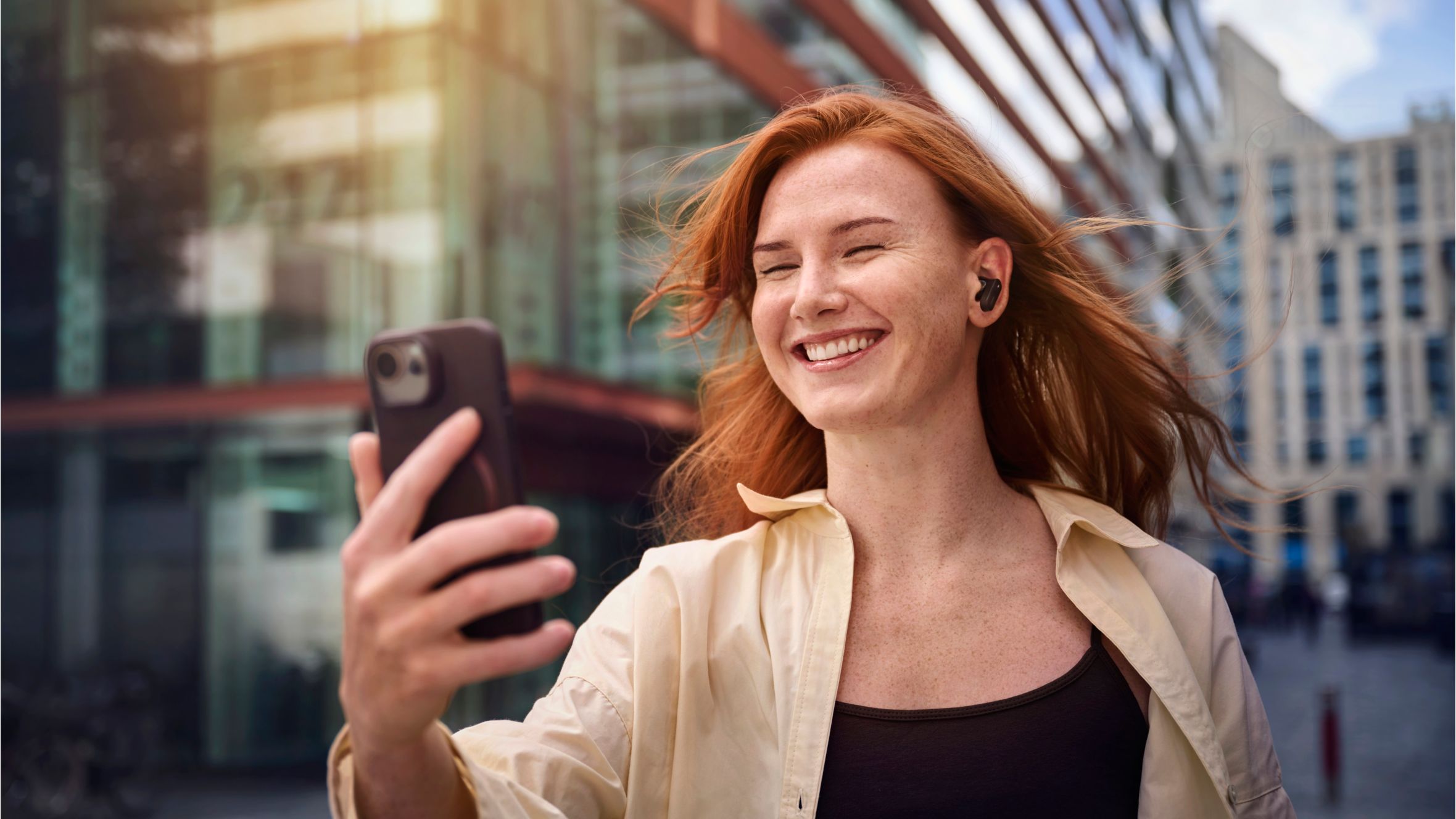 Woman on a video call while wearing Philips noise cancelling earbuds outdoors