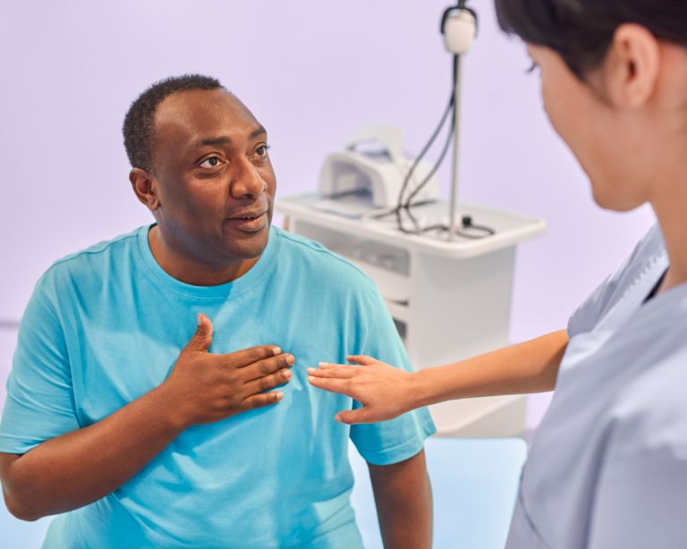 Patient on the table of the MRI scanner getting ready for a cardiac MRI exam and talking to the technologist