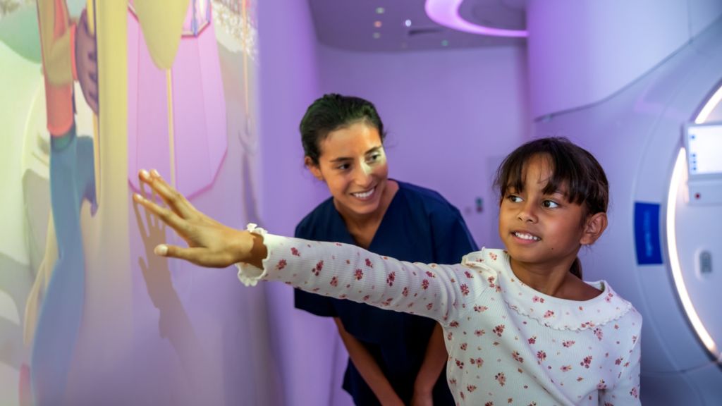 Girl playing with Ollie in Space theme prior to MRI exam and nurse watching – Pediatric Coaching solution
