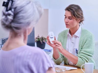 Medical professional demonstrating use of Philips wearable biosensor to patient