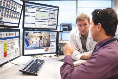 Intensive care physicians reviewing patient data in connected ICU command center
