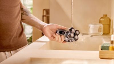 Hand rinsing Philips Norelco rotary head shaver under running water
