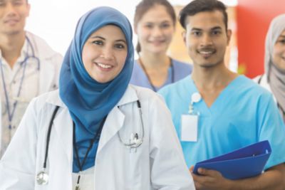 Tenaga kesehatan berbaju putih dan scrub saat briefing tim di rumah sakit