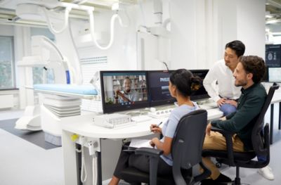 Philips employees in a medical imaging lab conducting a video meeting with a colleague on a monitor