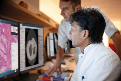 Dois clínicos analisam imagens de tomografia computadorizada e patologia em uma estação de trabalho de diagnóstico