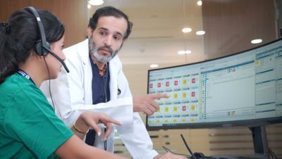 Clinician guiding healthcare professional reviewing patient monitoring data on computer screens