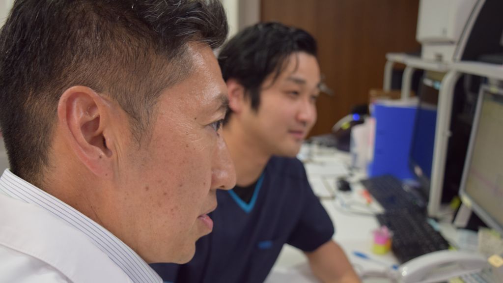 Hideki Koyasu and Katsuhiro Shiba looking at MRI results on screen
