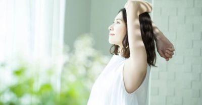 朝の光の中で窓辺でストレッチをする女性