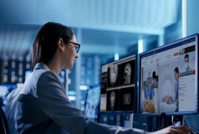 Telehealth imaging specialist monitoring MRI scans and remote consultation at digital workstation
