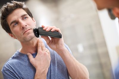 バスルームでフィリップスの電気シェーバーで髭を剃る男性