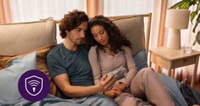 Eltern, die zusammen im Bett sitzen und ein Babyphone prüfen