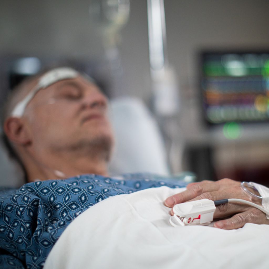 Doctor looking at mobile monitor screen at patient bedside