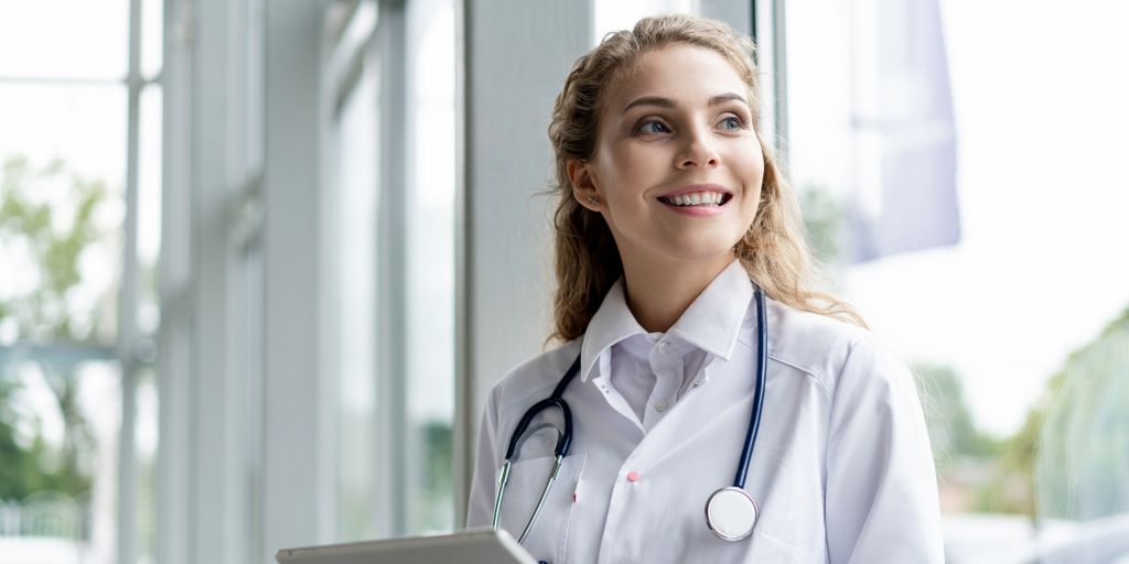 Jeune médecin femme souriante et portant un stéthoscope​