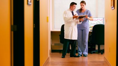 Two healthcare professionals discussing information on a tablet.