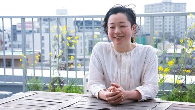 木のテーブルで野外インタビュー中に笑顔を浮かべる女性