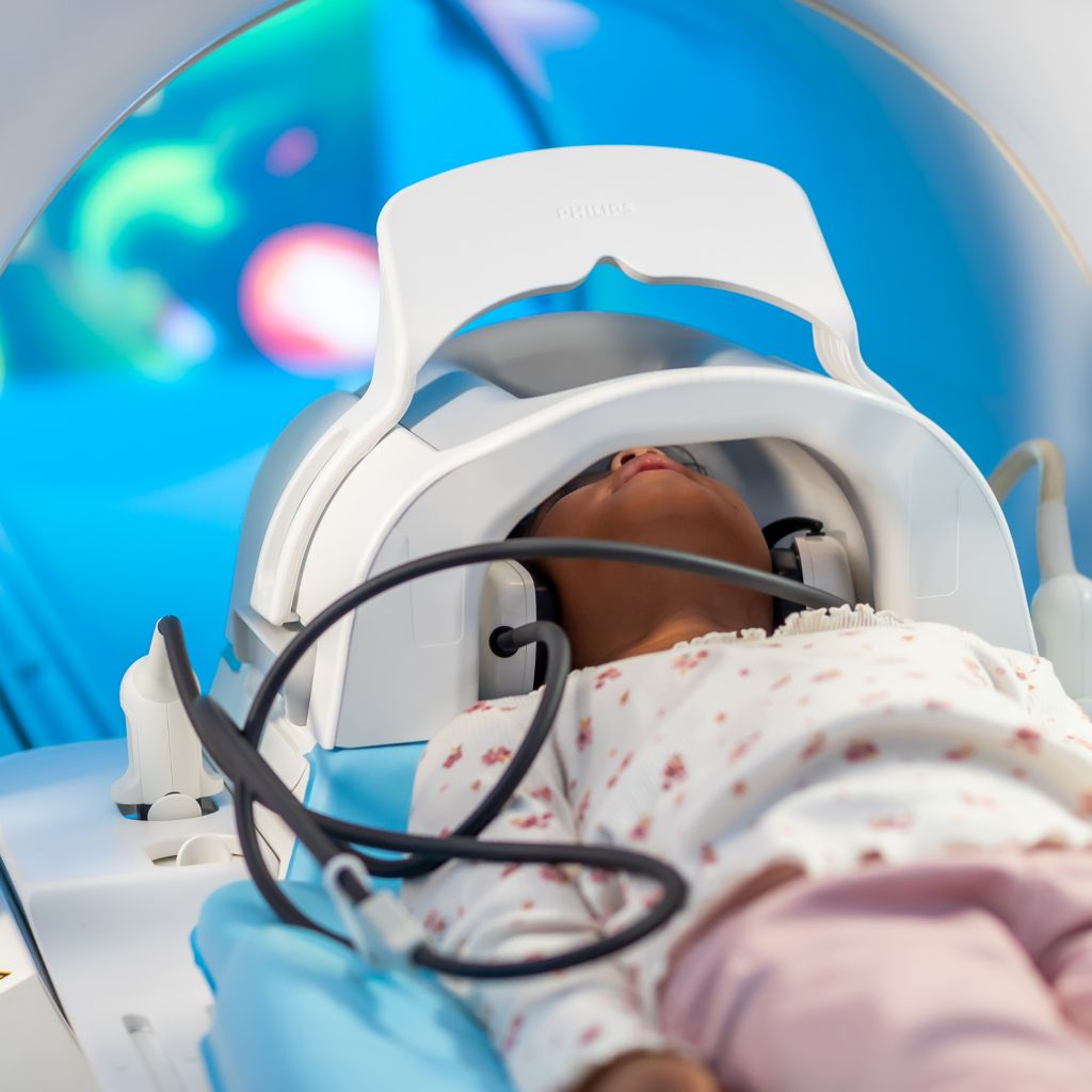 Girl on bed with headcoil and mirror just before the MRI exam with Ambient Experience In-bore Connect