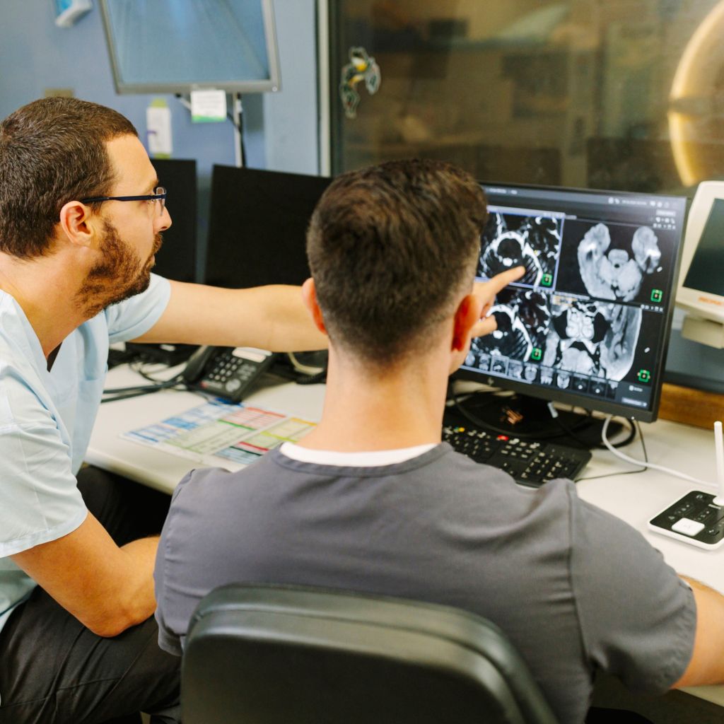 technologist and radiologist watching the screen of the MR console