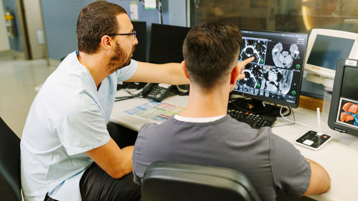 Radiologist and technologist behind the screen discussing MR images