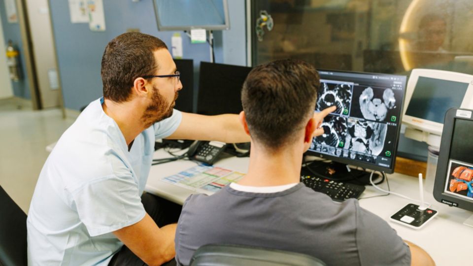 Radiologist and technologist behind the screen discussing MR images