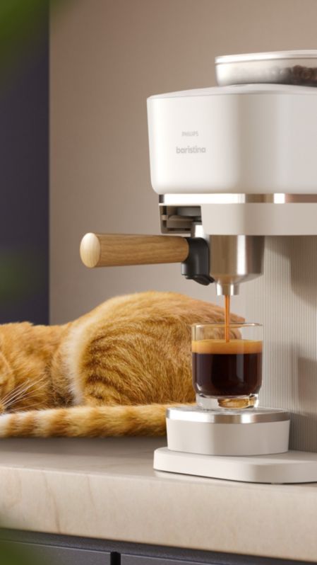 آلة Baristina من Philips وبجوارها قطة نائمة