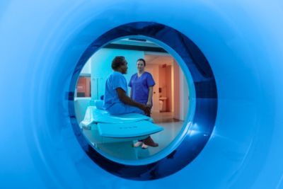 Clinician speaks with patient seated on table viewed through Philips CT scanner bore - Cropped
