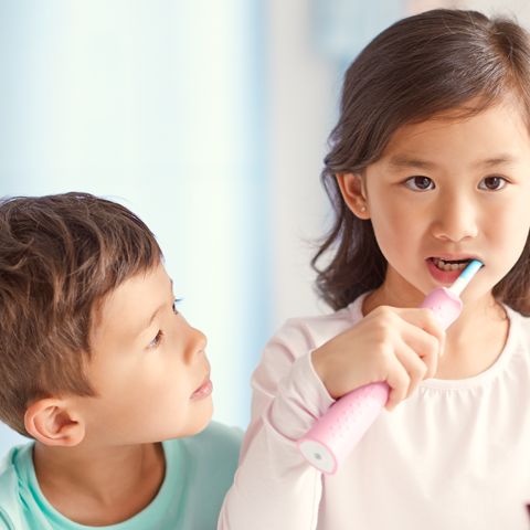 Two kids brushing with Sonicare For Kids at a sink.
