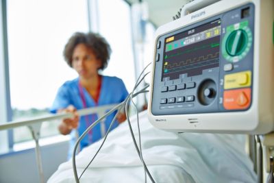 Moniteur patient Philips affichant les signes vitaux à côté d'un lit d'hôpital
