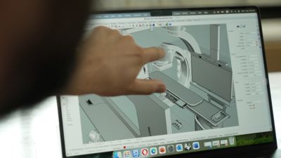 Engineer reviewing 3D CAD model on laptop screen
