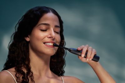 Woman using Sonicare electric toothbrush during daily oral care routine