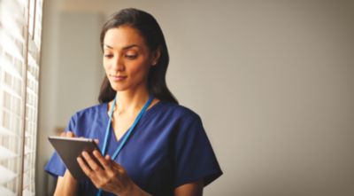 Mujer revisando los datos del paciente en la tablet junto a la ventana