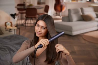 Kadın evde Philips saç düzleştirici kullanıyor