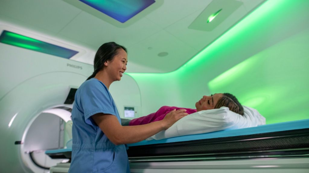 Radiographer comforting patient in a CT exam room with CT 7500 with Ambient Experience.