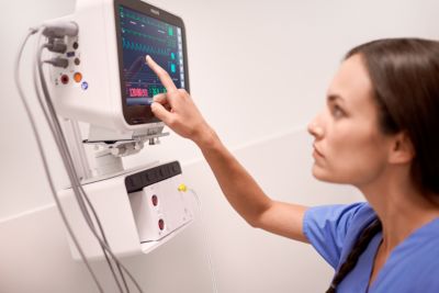 Enfermeira utilizando o monitor Philips Efficia Monitor Plus para visualizar os sinais vitais do paciente na UTI