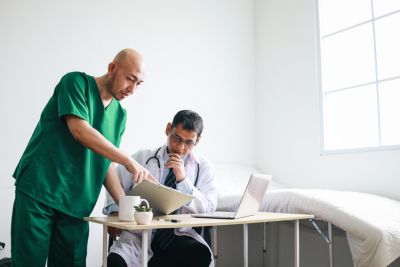 Two male doctors reviewing medical documents on a digital device