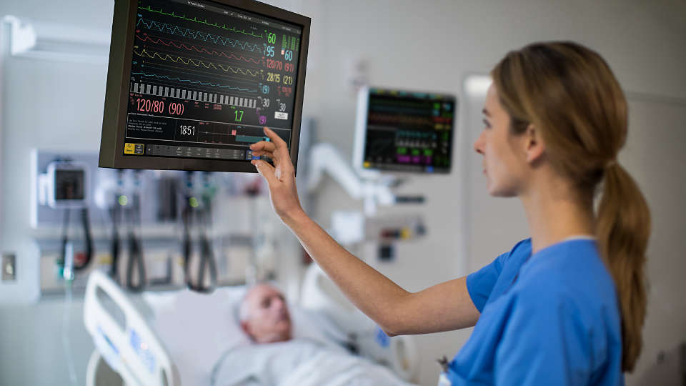A nurse looking at a remote bedside viewer