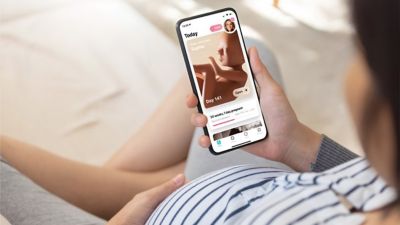 Pregnant woman using Pregnancy+ app on smartphone
