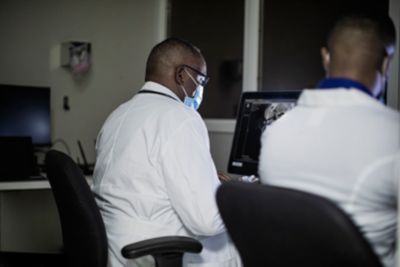 Healthcare professionals viewing data on a computer monitor.