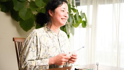植物を後ろに置いた電動歯ブラシを室内で持つ女性